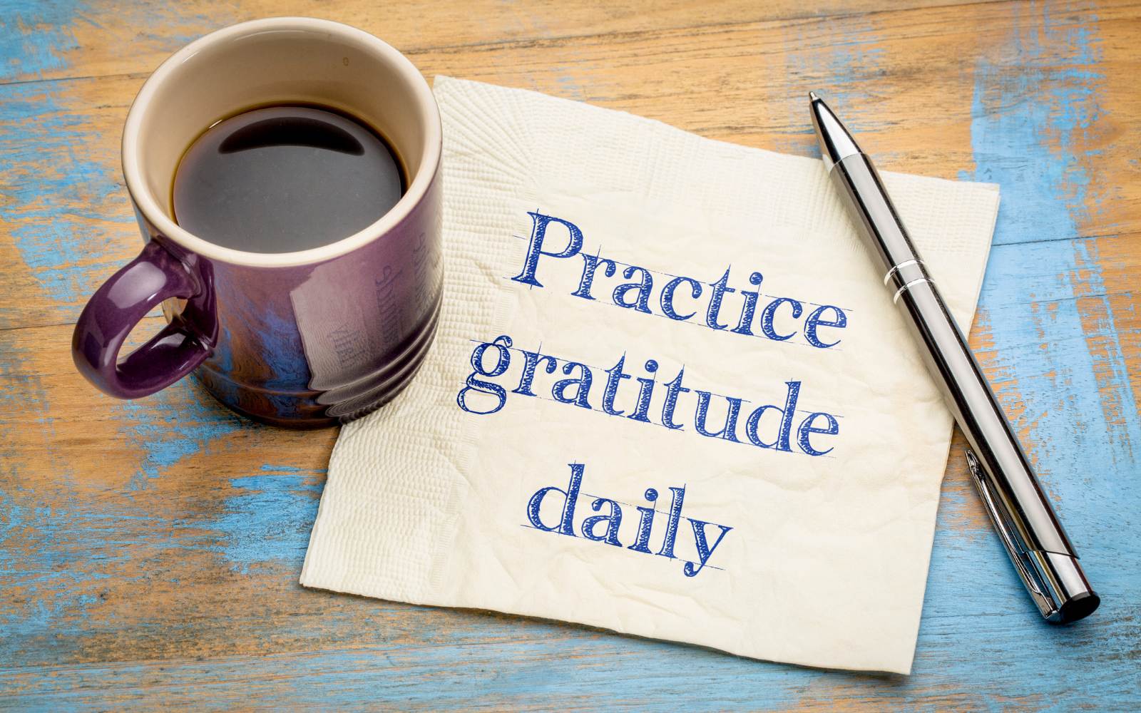 A cup of coffee and a napkin encouraging daily gratitude