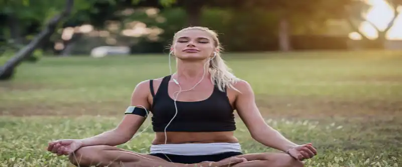 Female meditating on green grass and listening to morning meditation music. Morning meditation music can help you massively to have an effective meditation session. Learn more @ i-am-meditations.com