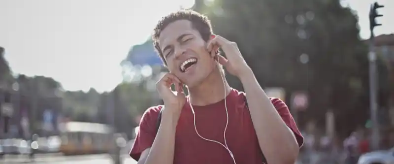 A man listening to I Am Meditation music on earbuds, feeling happy. Listening to meditation music can greatly boost your energy. learn more @ i-am-meditations.com