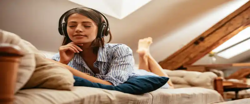 Unleash the positive power of music, by listening to meditation music on headphones or other devices. A female listening to Solfeggio Frequencies on Headphones @ I AM Meditations