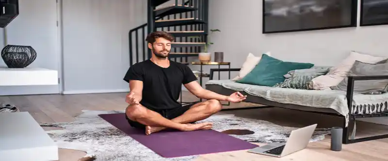 Male meditating on a purple yoga mat. The methods of meditation and its various forms, demonstrated by sitting quietly on the floor. Learn more @ i-am-meditations.com